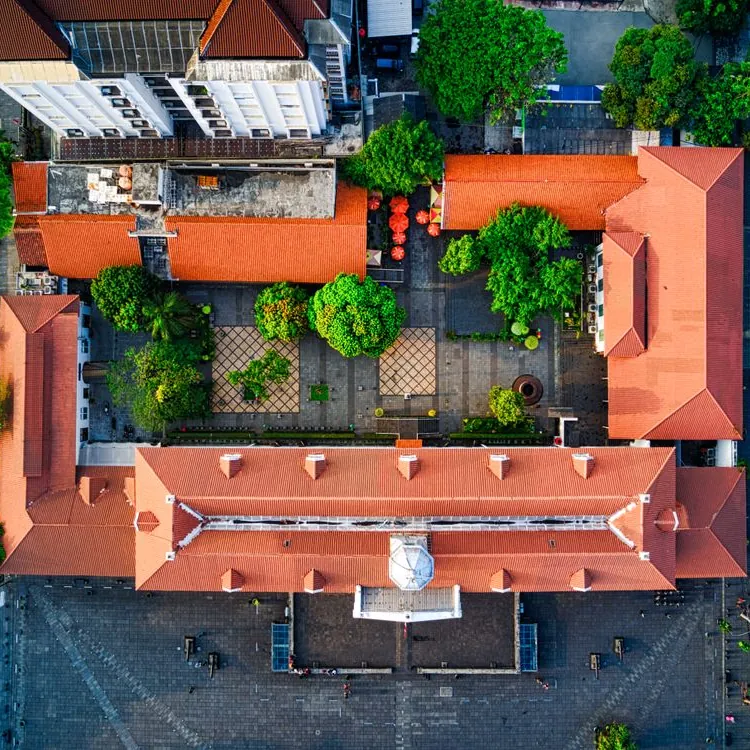Vue aérienne par drone d'un ensemble de bâtiments aux toits orange autour d'une cour arborée