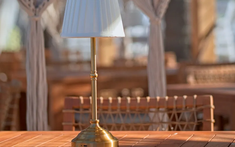 Lampe de table en laiton devant un rideau en macramé, photographie d'ambiance en lumière naturelle