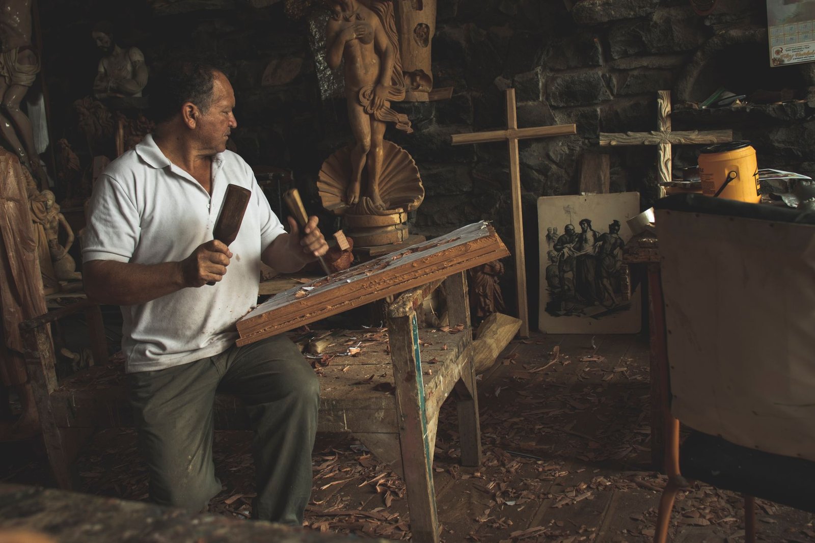 Elderly man skillfully carving wood in an art studio in San Antonio, Ecuador.
